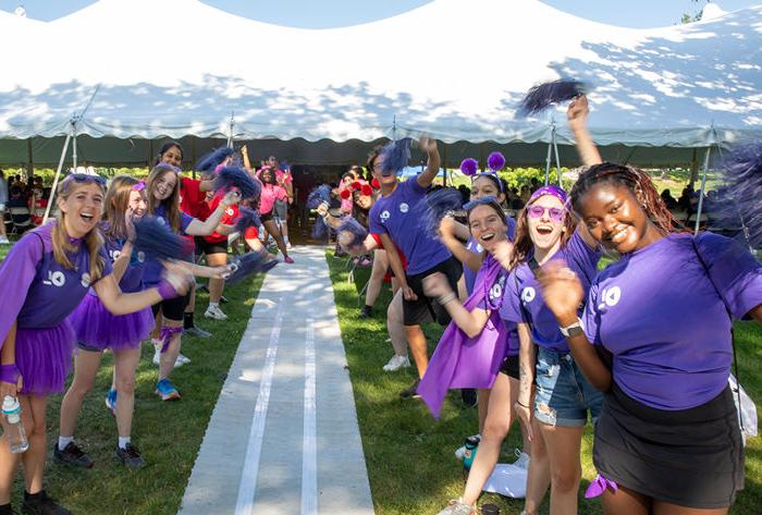 Students wearing bright colors cheer as they welcome new students.