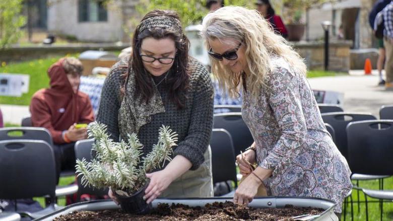 Berks 工作人员 member and student plant seeds in campus garden